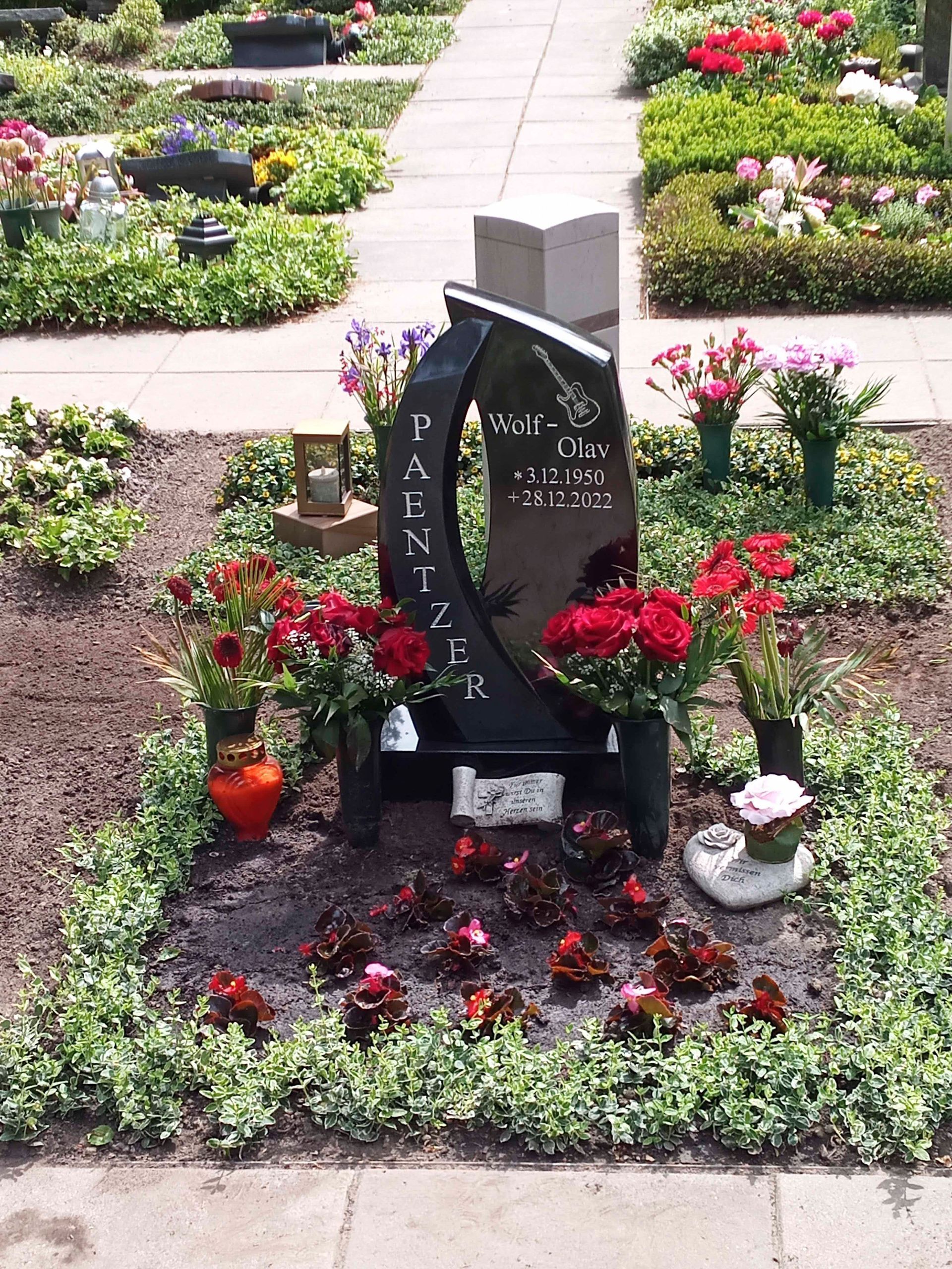 Ein Grab auf einem Friedhof, umgeben von Blumen und Pflanzen