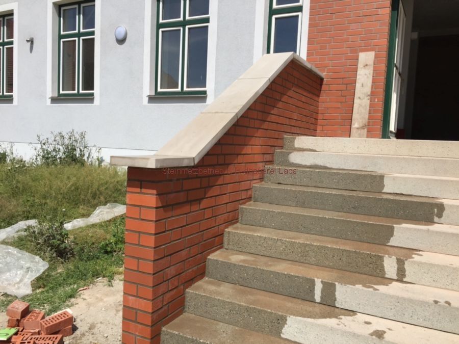 Eine Backsteinmauer mit Treppen, die zu einem Gebäude hinaufführen