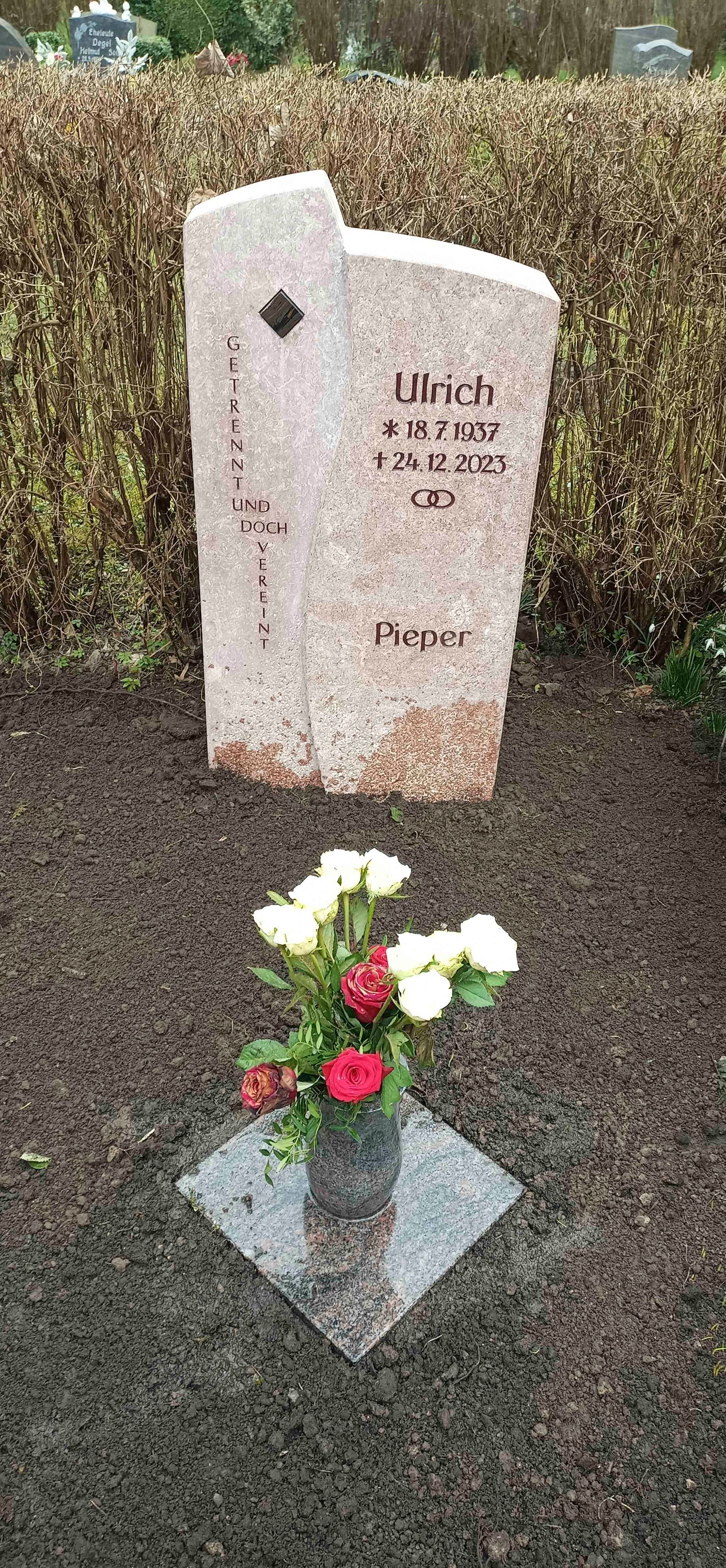 Ein Grab mit einer Blumenvase davor.