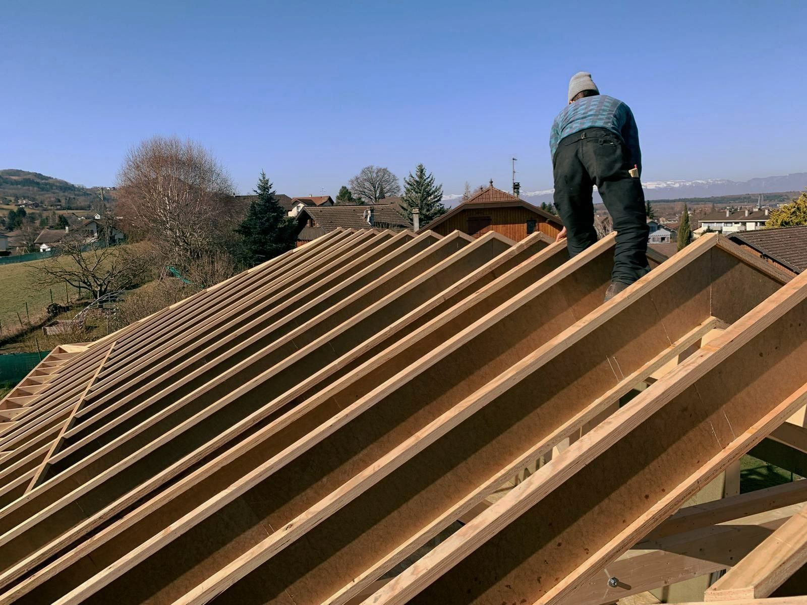 Un artisan qui travaille debout sur la charpente d'une construction à ossature en bois