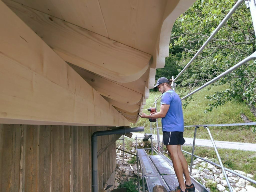 Un artisan qui visse un élément de toiture sur une maison à ossature en bois