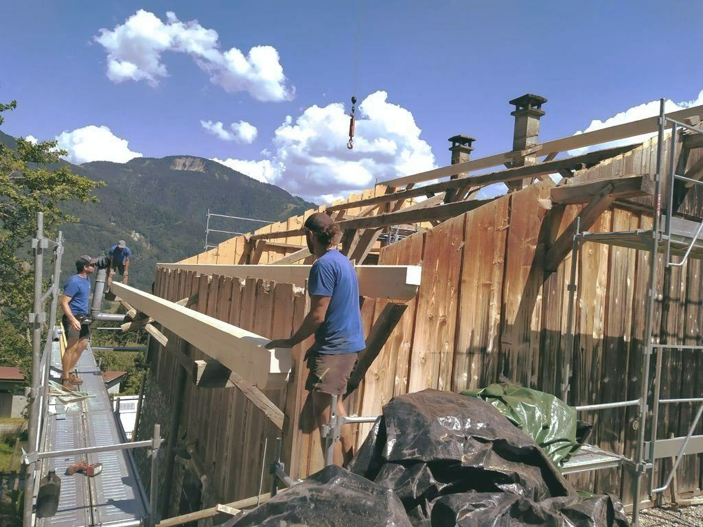 Trois artisans qui travaillent sur la charpente d'une maison à ossature en bois