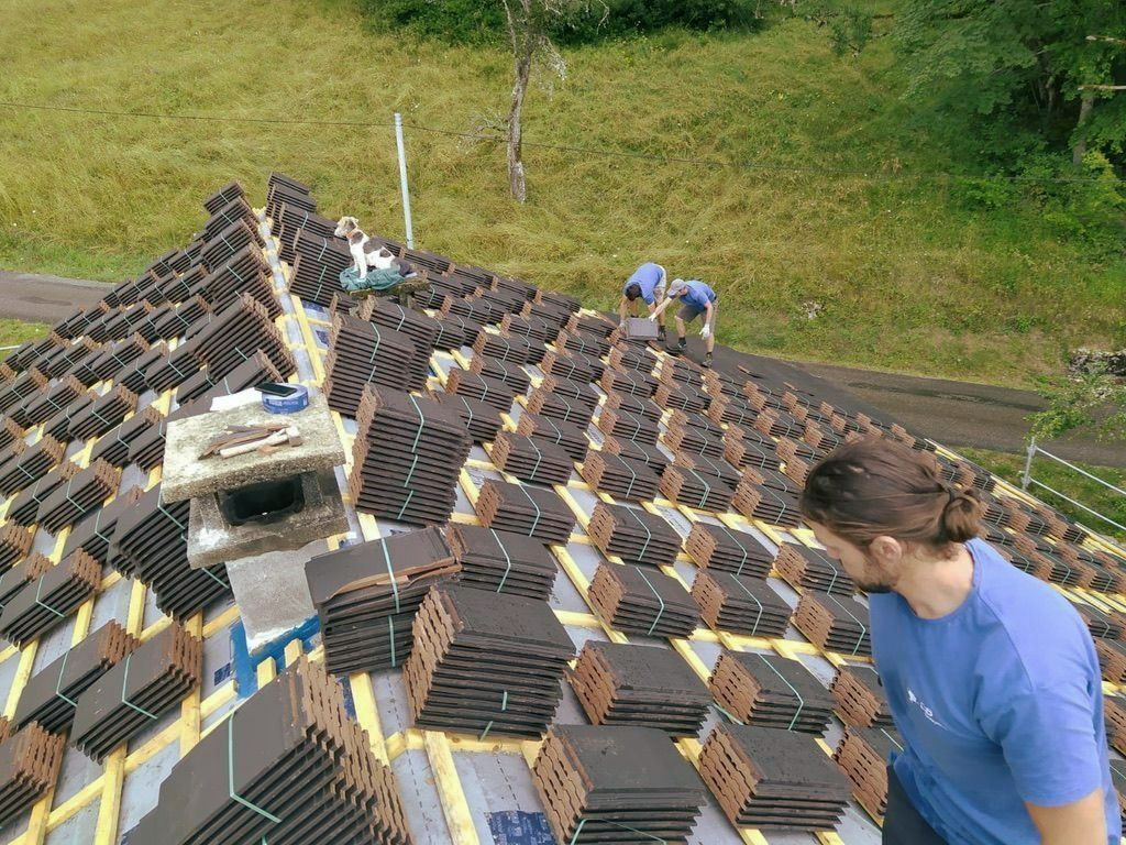 Trois artisans qui travaillent sur la couverture d'un toit de maison