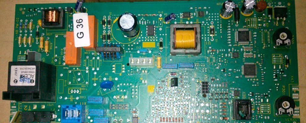 Una placa de circuito impreso verde con componentes electrónicos, incluidos relés, condensadores y un transformador amarillo.