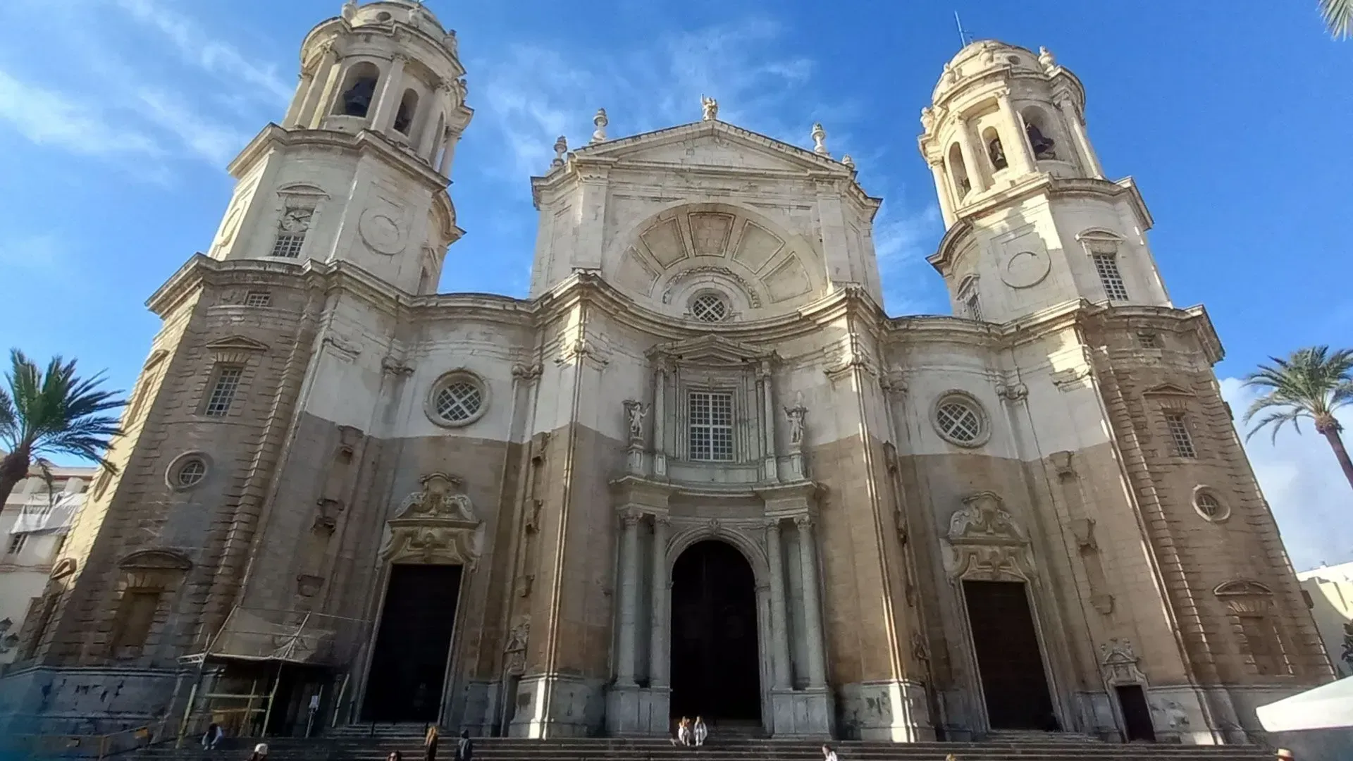 Vista frontal de una gran catedral beige con torres gemelas contra un cielo azul.