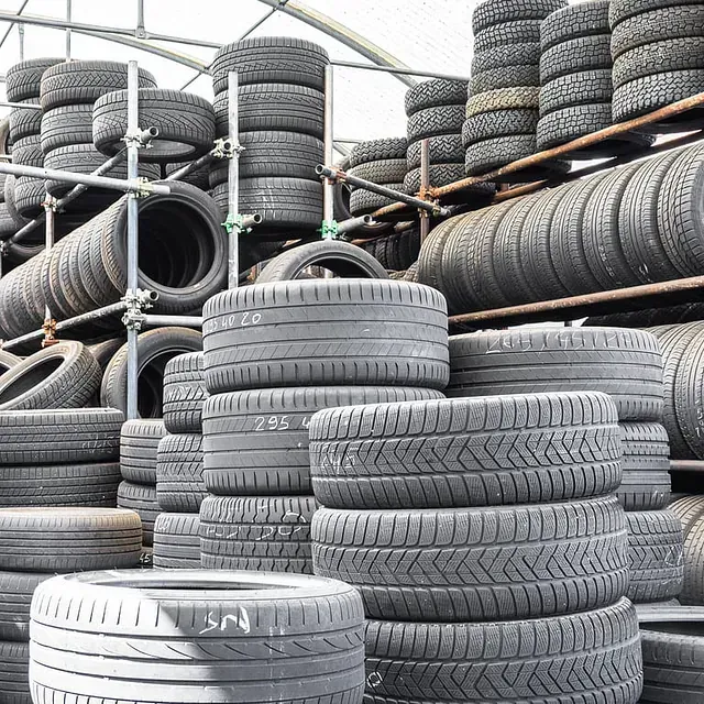 Pilas de neumáticos usados en un entorno industrial, probablemente una instalación de reciclaje o almacenamiento.