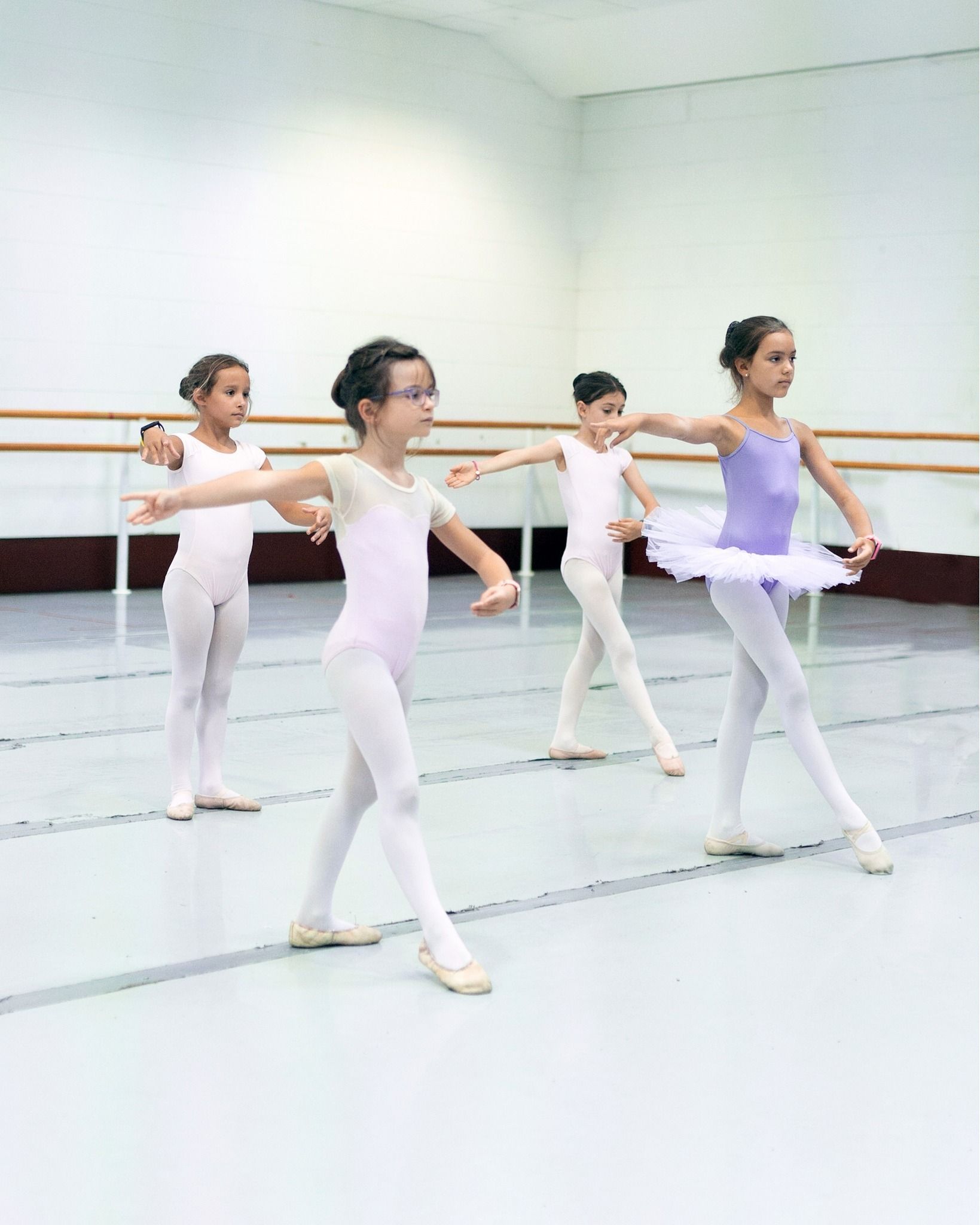 Un grupo de chicas jóvenes están practicando ballet en un estudio de baile.
