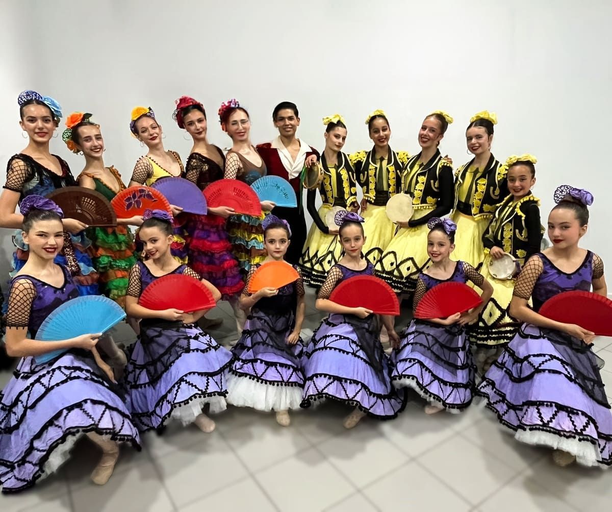 Grupo de bailarines con coloridos trajes, posando con sus fans en un estudio.