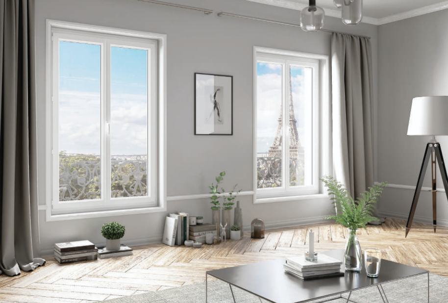 Salon avec vue sur la ville depuis deux fenêtres, murs gris, tour Eiffel visible.