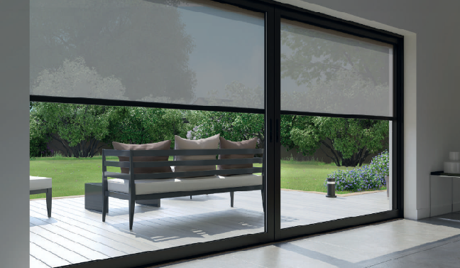 Porte-fenêtre coulissante avec stores clairs partiellement abaissés. Terrasse extérieure aménagée avec un banc et de la végétation.