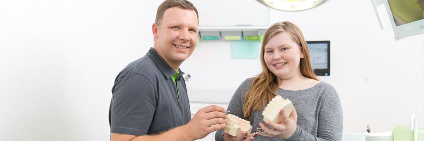 Zahnarztpraxis Robert Gutowski – Zwei Personen halten ein Modellgebiss