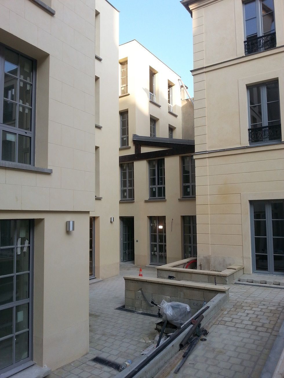 Passage entre deux grands immeubles en pierre de couleur claire.
