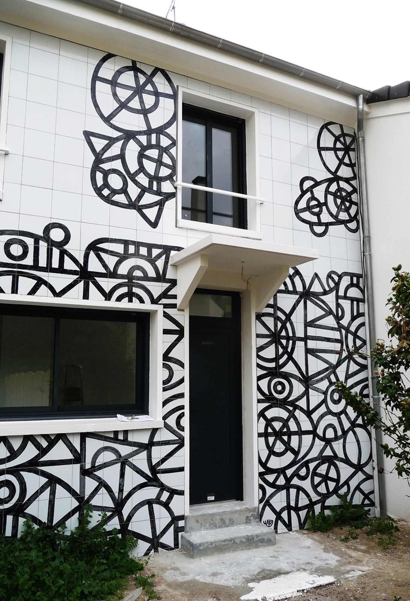 Façade d'une habitation avec des éléments en fer forgé donnant l'impression de voir une œuvre d'art.