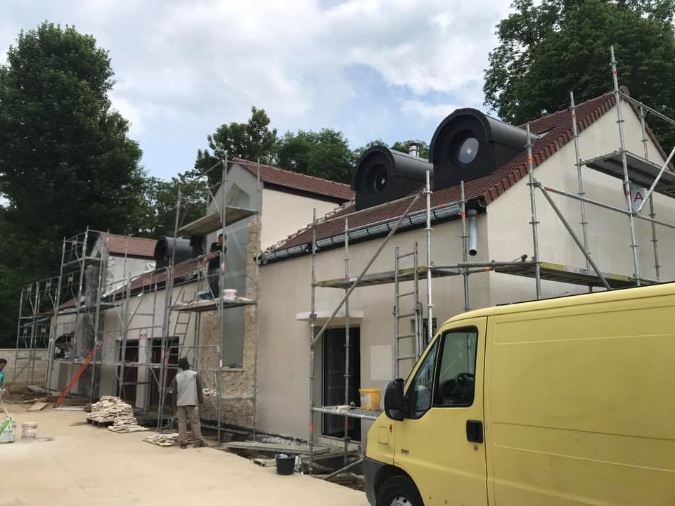 Des artisans sont en train de réaliser des travaux sur la façade d'une habitation.