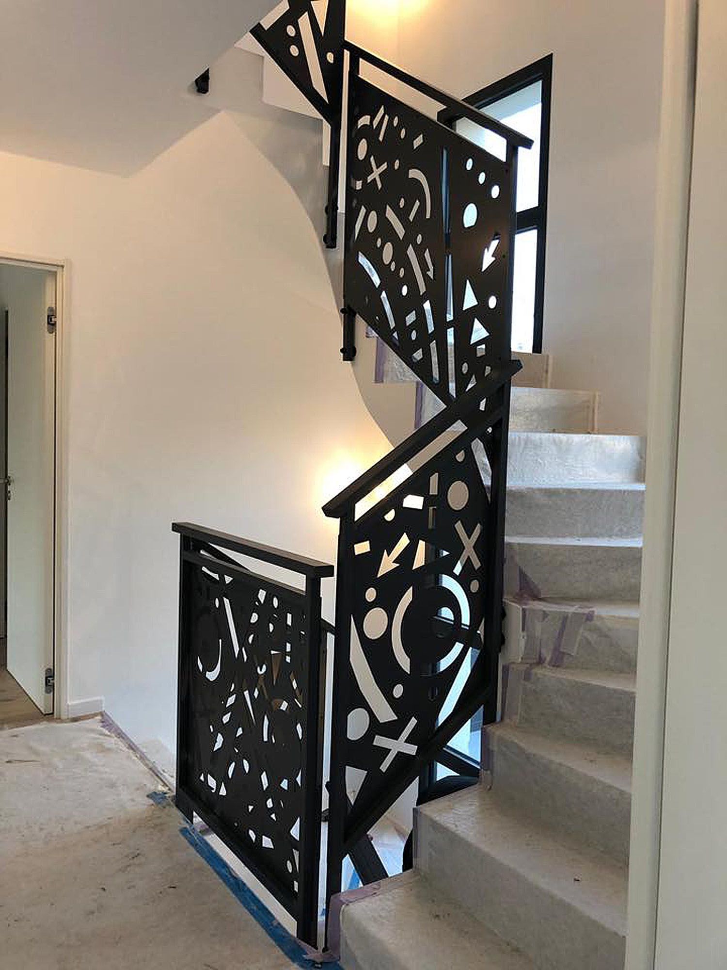 Escalier en colimaçon avec un garde-corps en fer forgé composé de multiples formes.