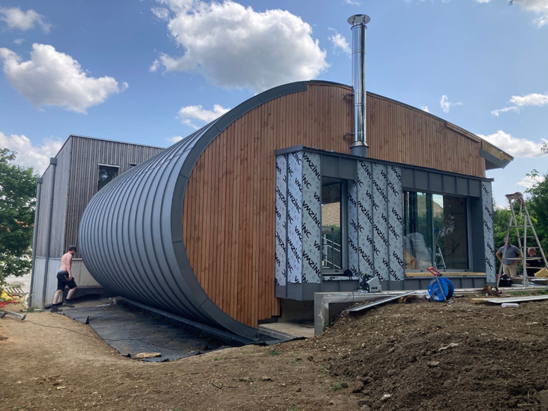 Une habitation avec un bardage en bois avec un grand arrondi sur l'un des murs.