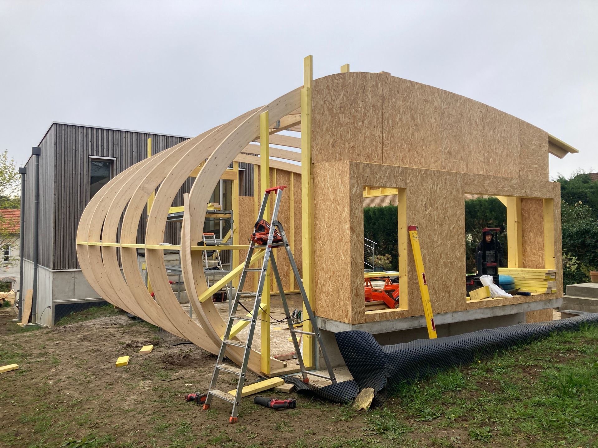 Construction en cours d'une habitation à ossature en bois avec un grand arrondi sur l'un des murs.