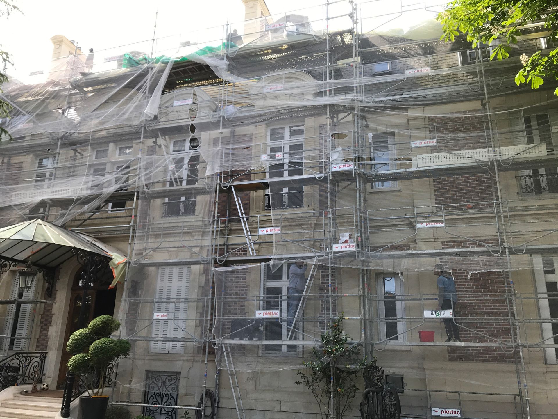 Façade d'un grand immeuble recouvert d'échafaudage.