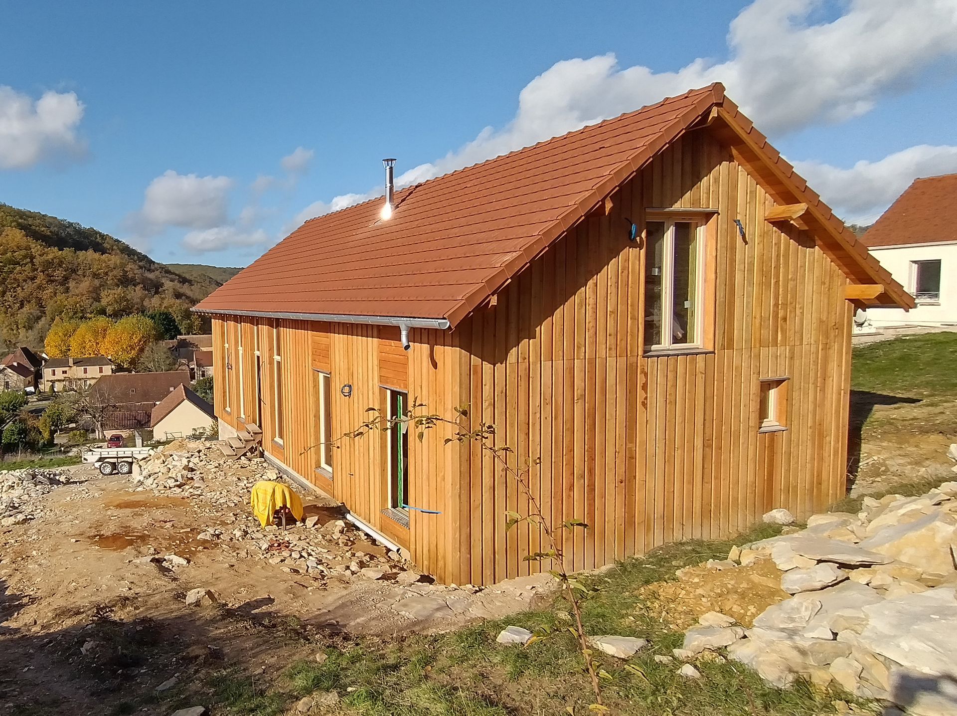 Maison avec un bardage en bois clair sur un terrain en construction.