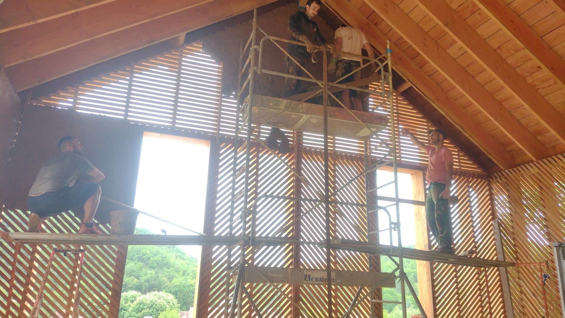 Plusieurs artisans sur un échafaudage à l'intérieur d'une maison à ossature en bois.