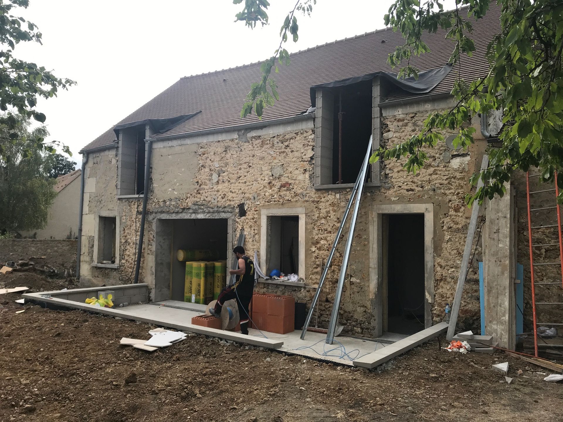 Un artisan devant une habitation sans fenêtres en cours de restauration.