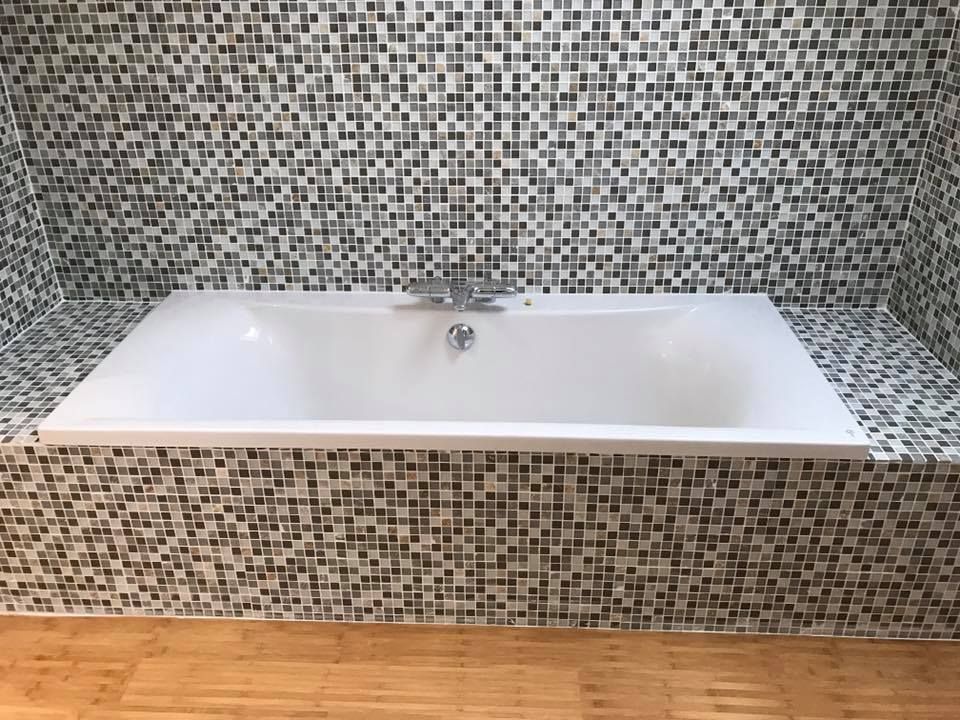 Baignoire au contour et mur entièrement en faïence.