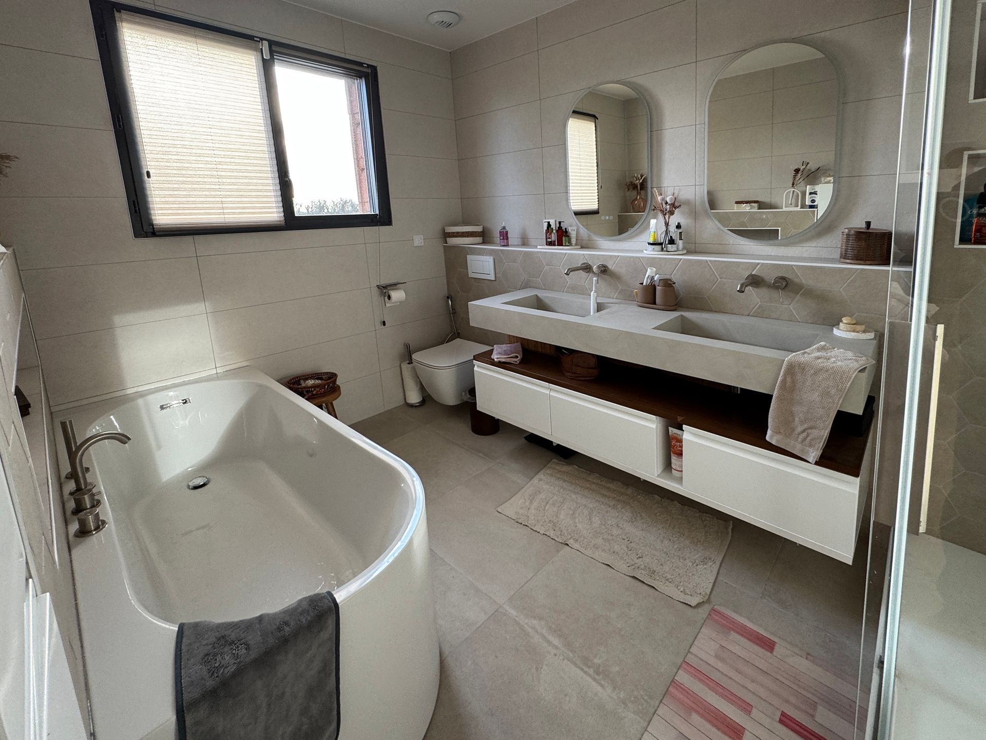 Salle de bains avec une baignoire et deux vasques au fond de la pièce.