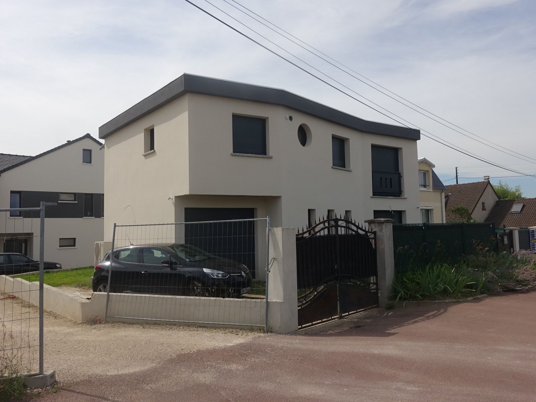 Maison d'un lotissement avec un véhicule noir.