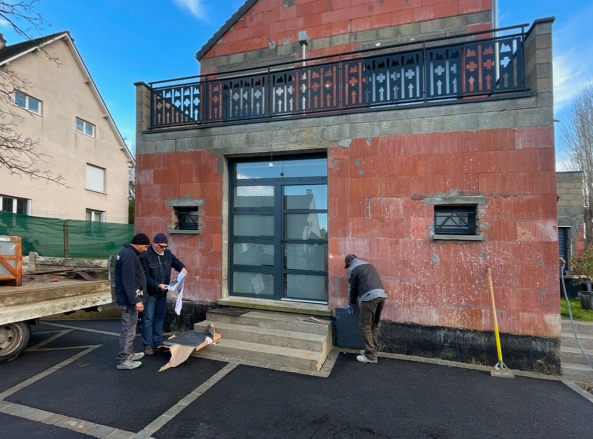 Trois personnes devant une habitation en construction.
