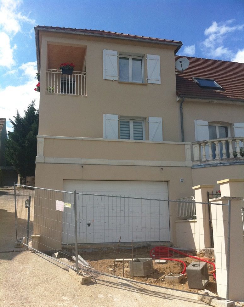 Extension de maison comprenant un garage et deux étages supplémentaires.