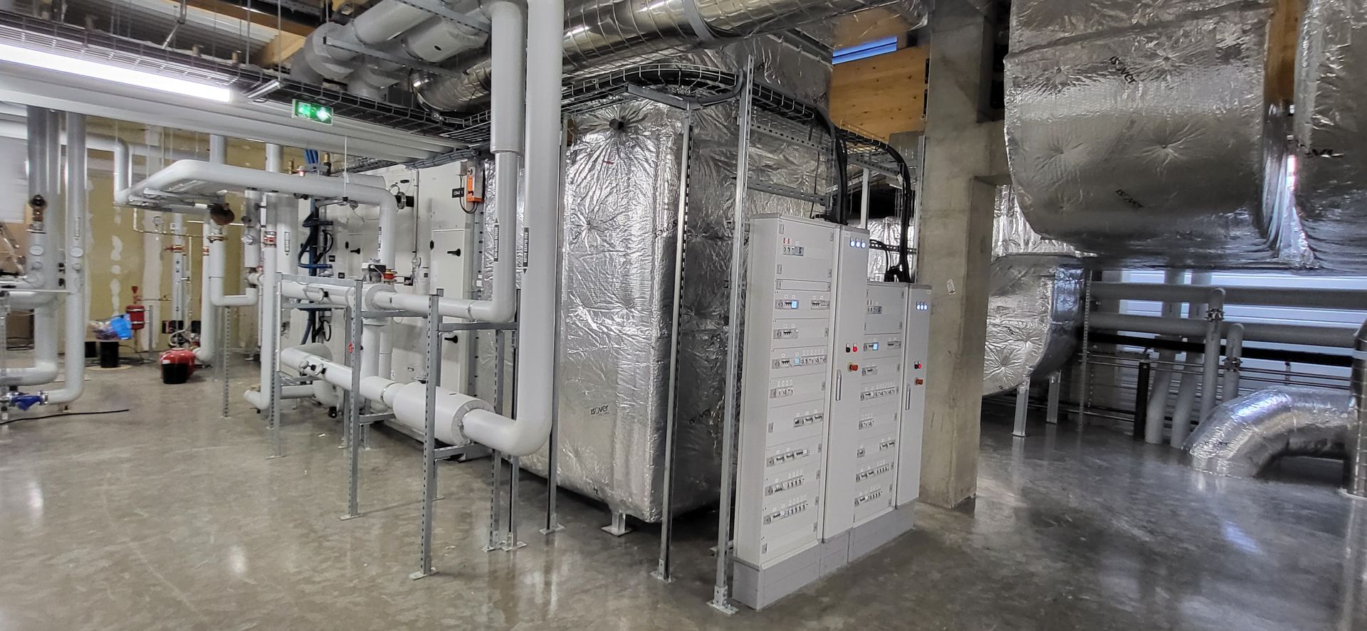Conduits et tuyaux de CVC isolés dans une salle des machines inondée avec un sol réfléchissant