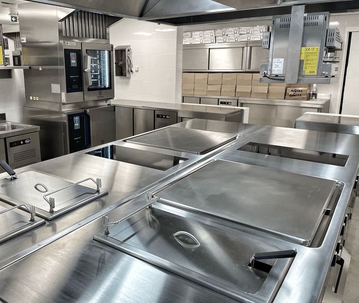 Cuisine commerciale en acier inoxydable avec comptoirs, éviers, fours et hottes aspirantes, vide et propre.