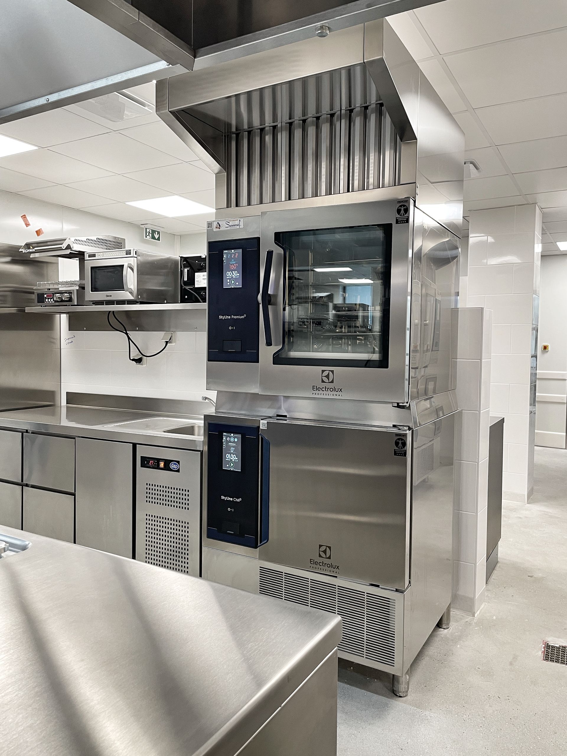 Fours commerciaux en acier inoxydable dans une cuisine industrielle lumineuse avec hotte aspirante au plafond