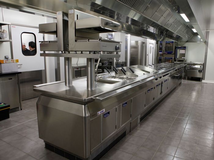 Ligne de cuisine commerciale en acier inoxydable avec éviers, comptoirs et équipements suspendus dans une cuisine industrielle propre