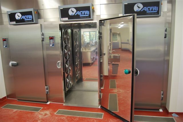 Portes de chambres froides industrielles en acier inoxydable avec tapis de sol rouges et panneaux de commande bleus