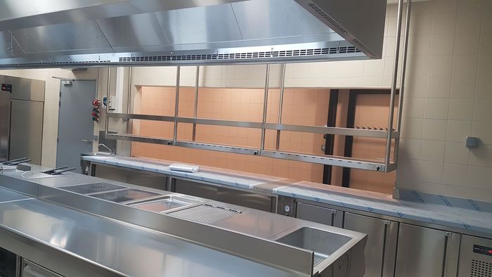 Cuisine commerciale vide en acier inoxydable avec hotte, comptoir de préparation et passe-plat