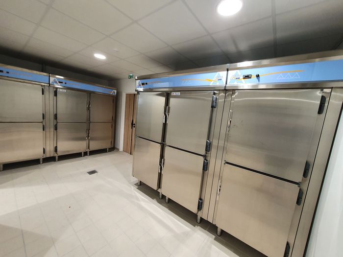 Chambre froide industrielle vide avec portes en acier inoxydable et sol carrelé blanc