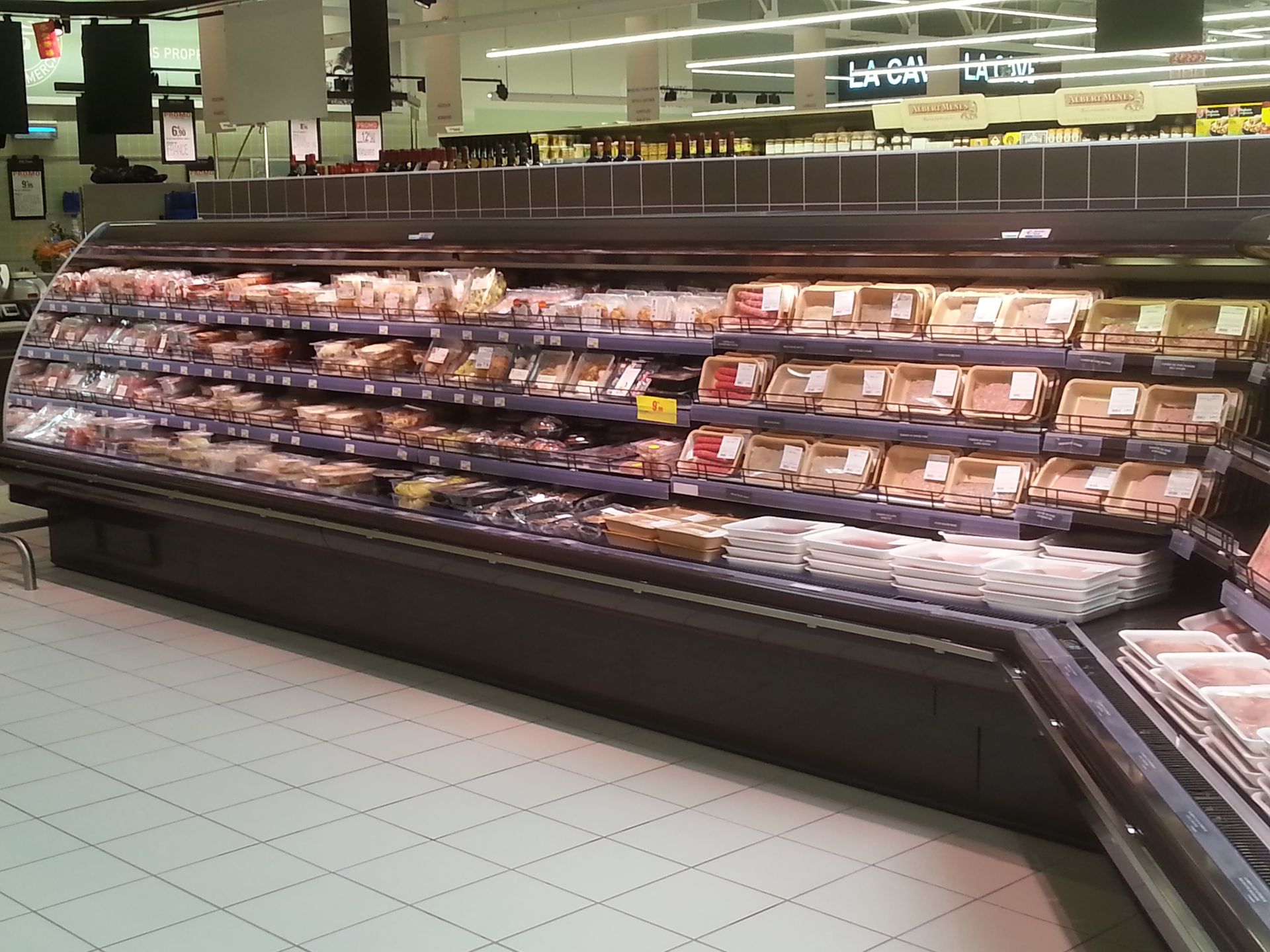 Vitrine réfrigérée de supermarché remplie de viandes emballées et de plats préparés