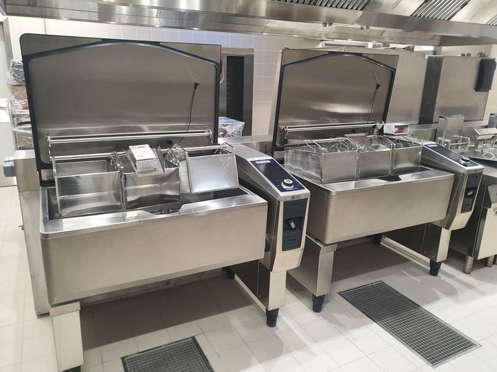 Stations de service de cafétéria en acier inoxydable avec plateaux et bacs alimentaires sous une hotte de buffet