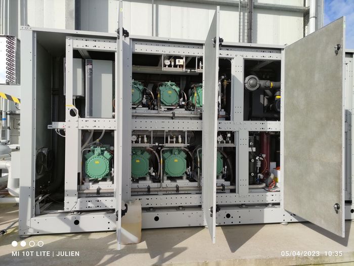 Armoires électriques ouvertes avec ventilateurs verts à l'intérieur, disposées dans un environnement industriel.