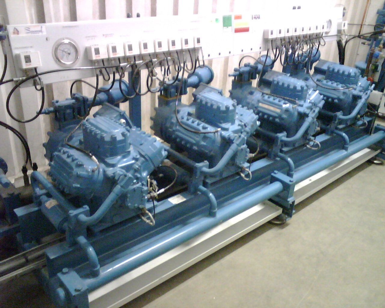 Rangée de compresseurs industriels bleus et de tuyaux dans une salle des machines
