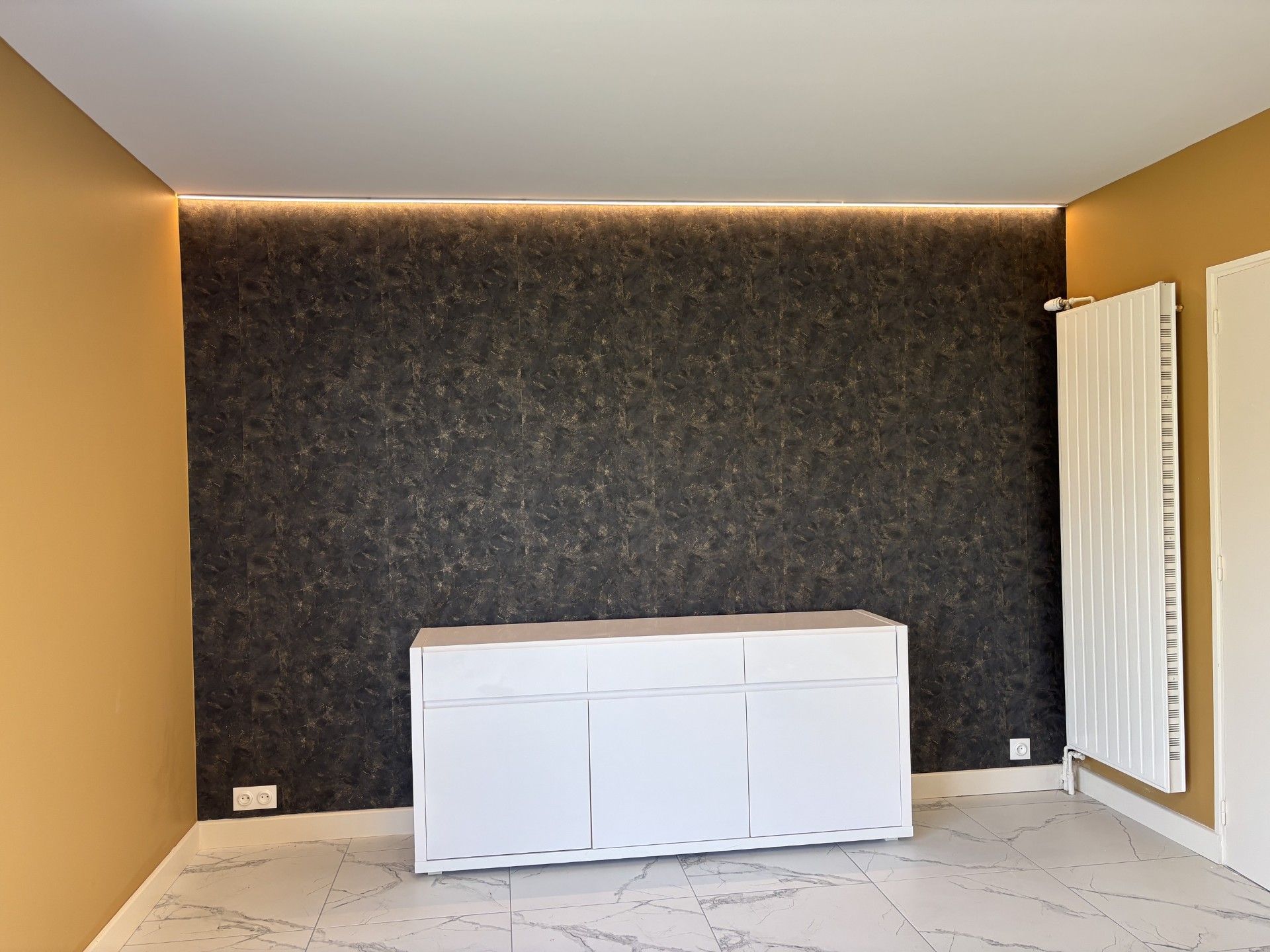 Pièce vide avec un mur d'accent foncé, une armoire blanche et des fenêtres sur la droite.