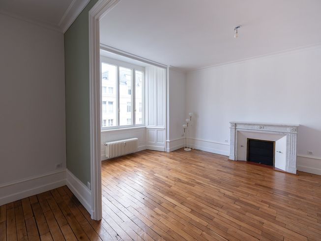 Salon lumineux avec canapés blancs, escalier en bois et grand vaisselier dans un loft spacieux et ouvert