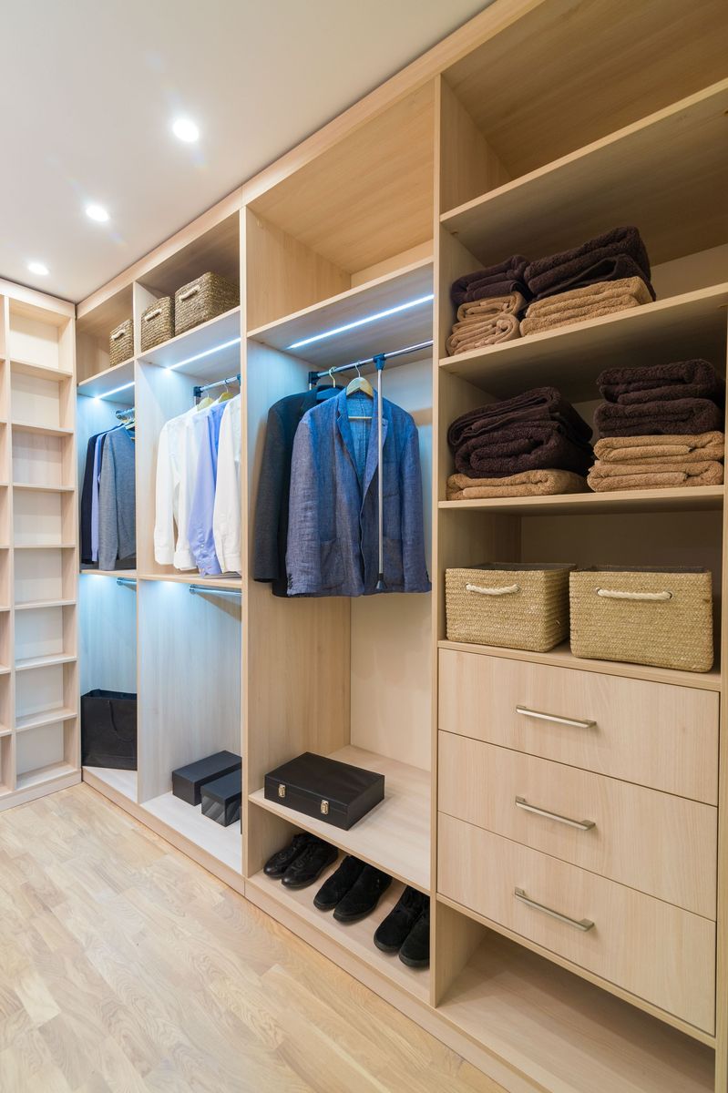 Dressing intégré avec penderie, étagères, paniers, tiroirs et chaussures sur un parquet clair