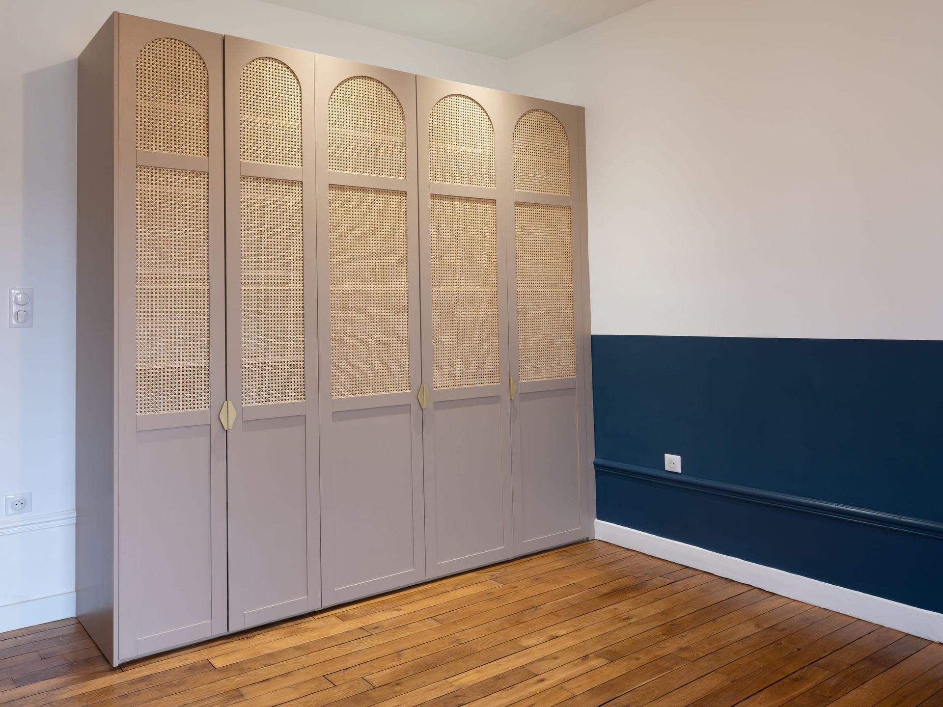 Chambre lumineuse avec bibliothèque intégrée au-dessus d'un lit violet et une fenêtre sur la droite