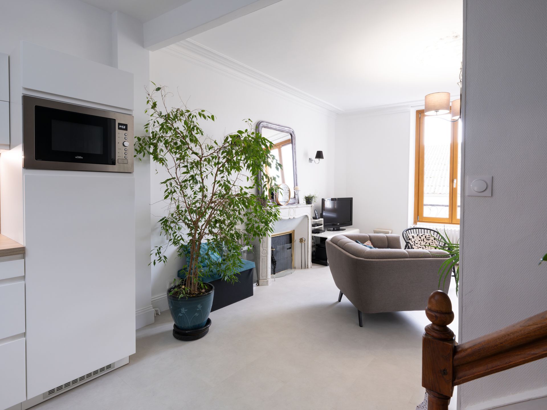 Salon moderne et lumineux avec canapés en osier, grandes fenêtres et intérieur blanc ouvert