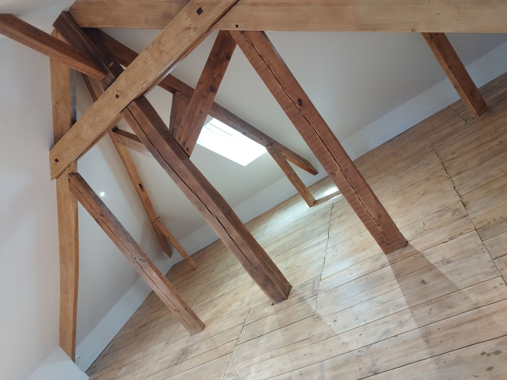 Poutres apparentes au plafond et puits de lumière au-dessus d'un mur intérieur en bois clair