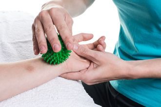 Mann macht Übungen auf einem Gymnastikball, Unterstützung durch Ergotherapeut