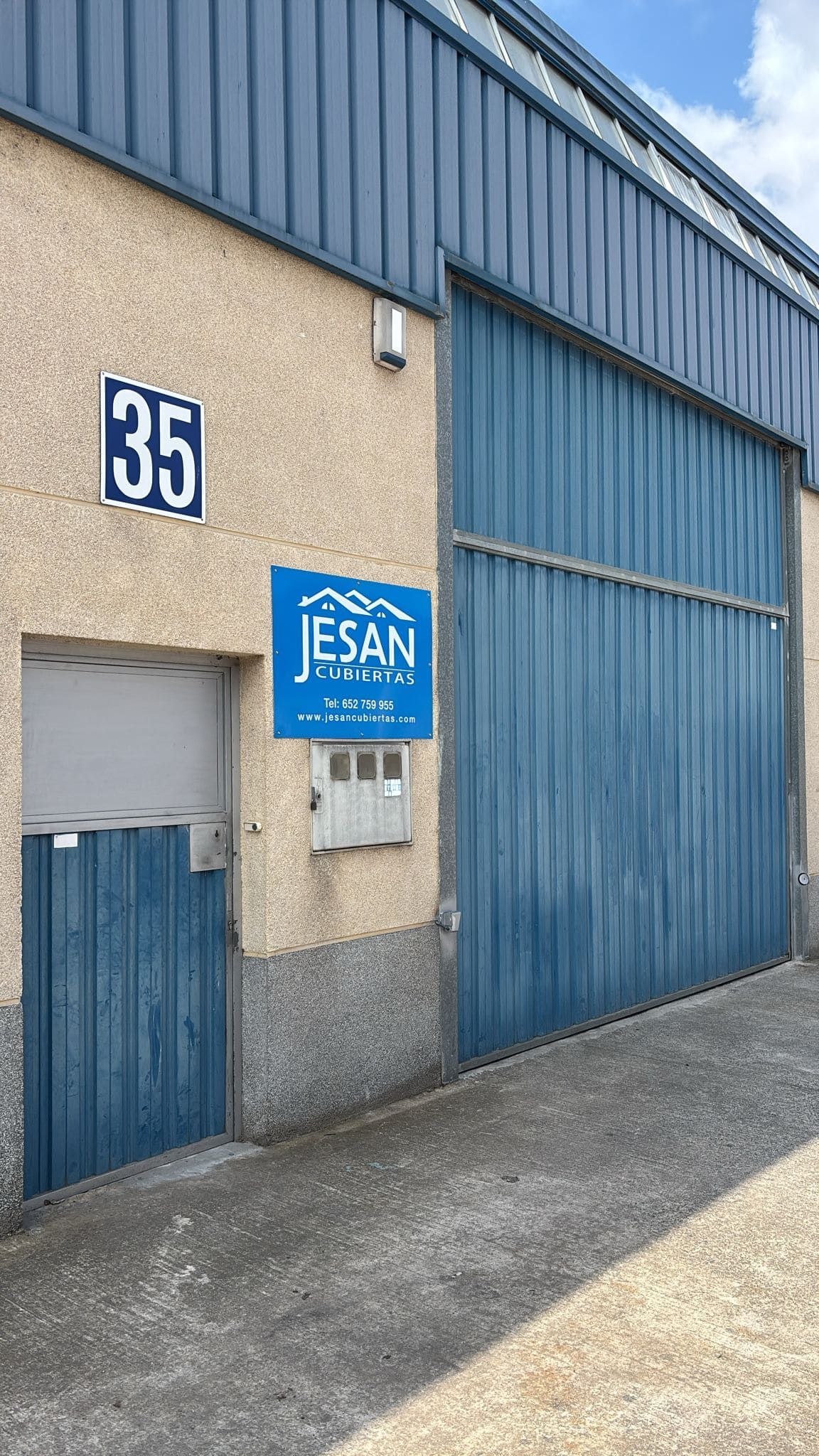 Cuatro trabajadores con uniformes azules y cascos instalan tejas rojas en el tejado de una vivienda.
