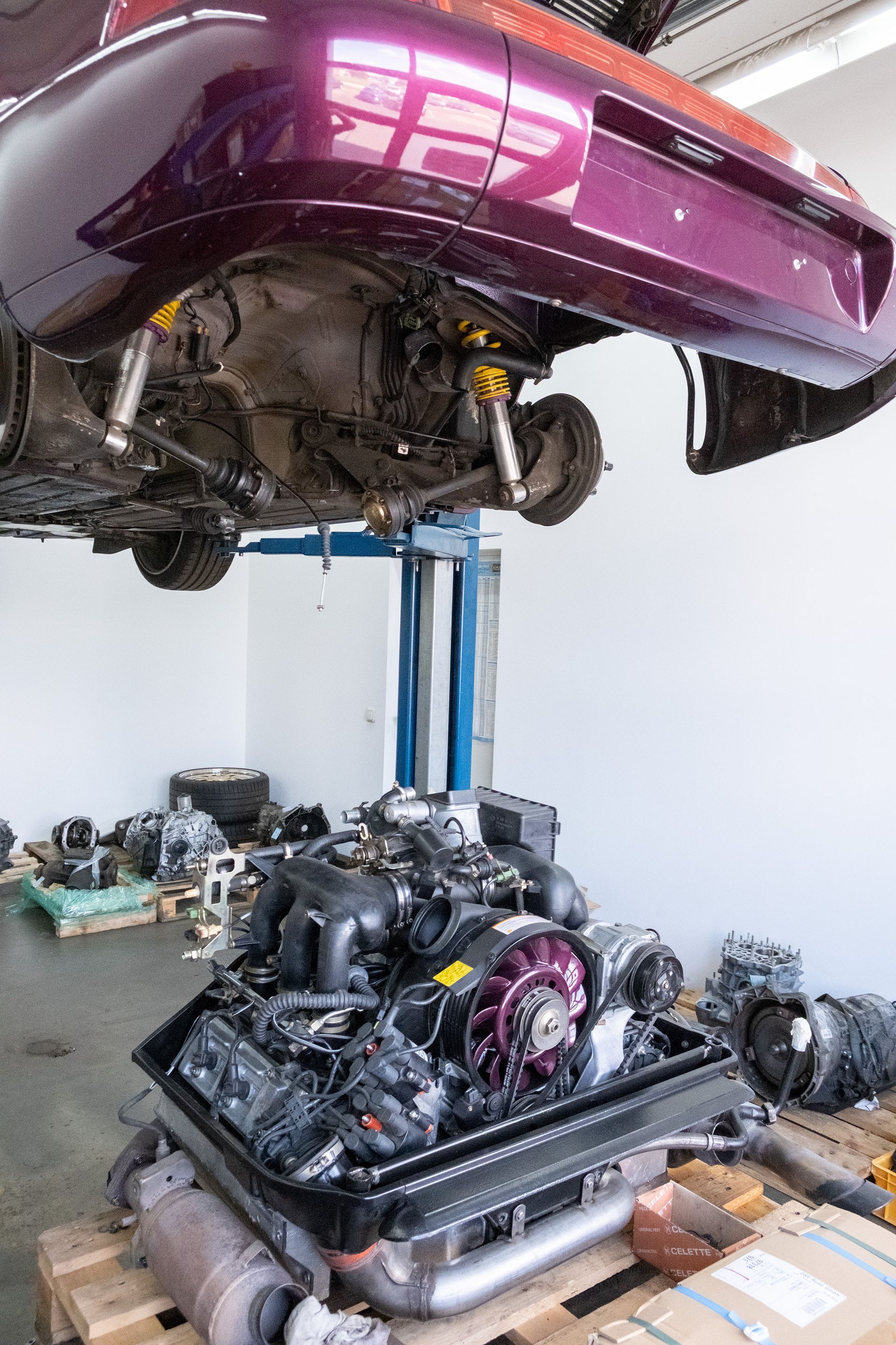 Außenansicht eines zweistöckigen Kfz-Werkstattgebäudes mit davor geparkten Autos.